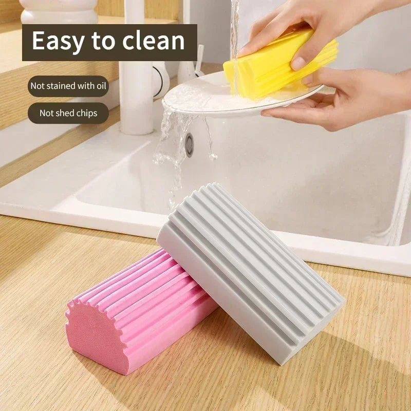 Two cleaning blocks, one pink and one gray, with a hand using a yellow sponge in a kitchen setting.

